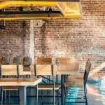 restaurant scene of custom wood table, seating chairs and a metal hanging light fixture