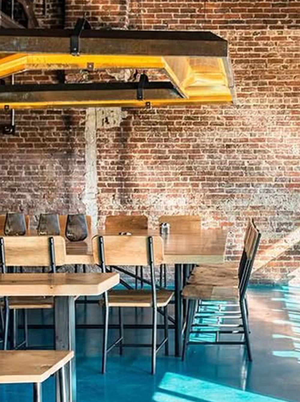 restaurant scene of custom wood table, seating chairs and a metal hanging light fixture