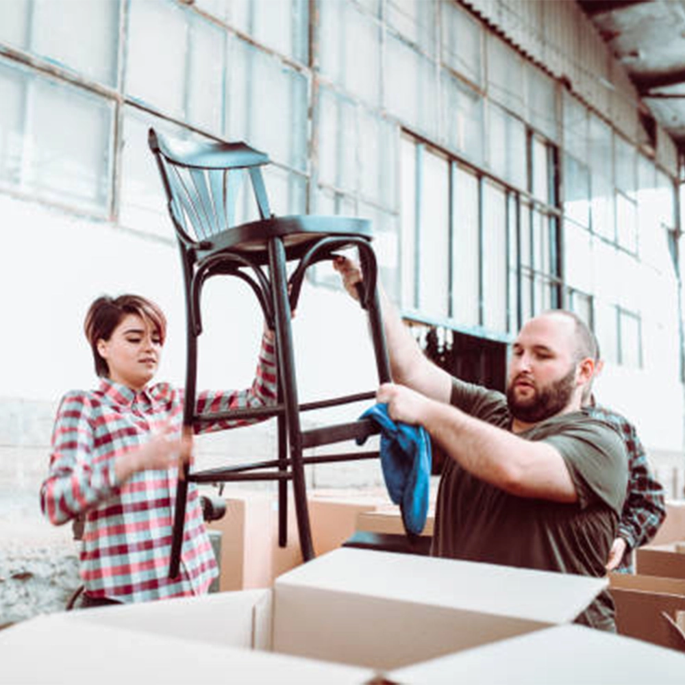 two harvest custom team members packaging a custom made wooden chair